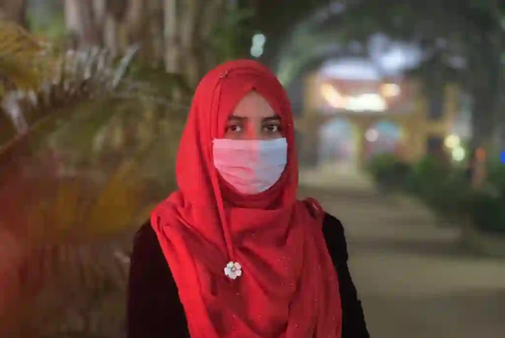 Photo of Antara Sadia Siddika, Client Relationship Manager, standing outdoors in a red outfit with a scenic background.