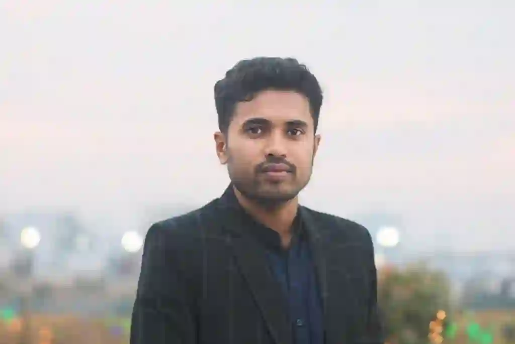 Photo of Rakib Hosen, Graphics Designer, standing outdoors in a suit with a blurred cityscape background.